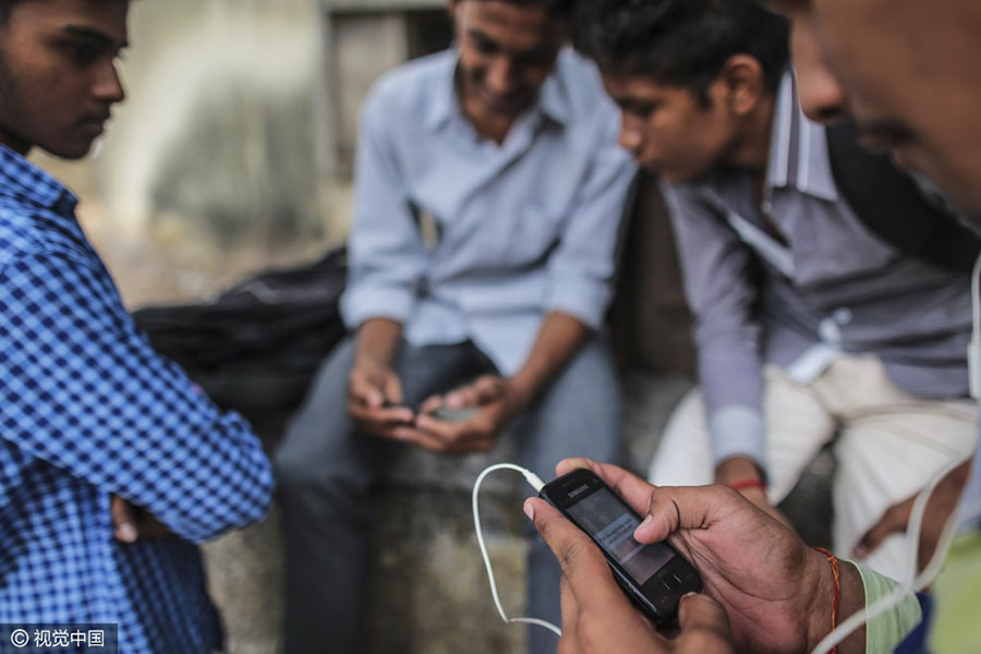 Um pedestre (frente) usa um smartphone fabricado pela Samsung, em Mumbai, na índia. [CFP]