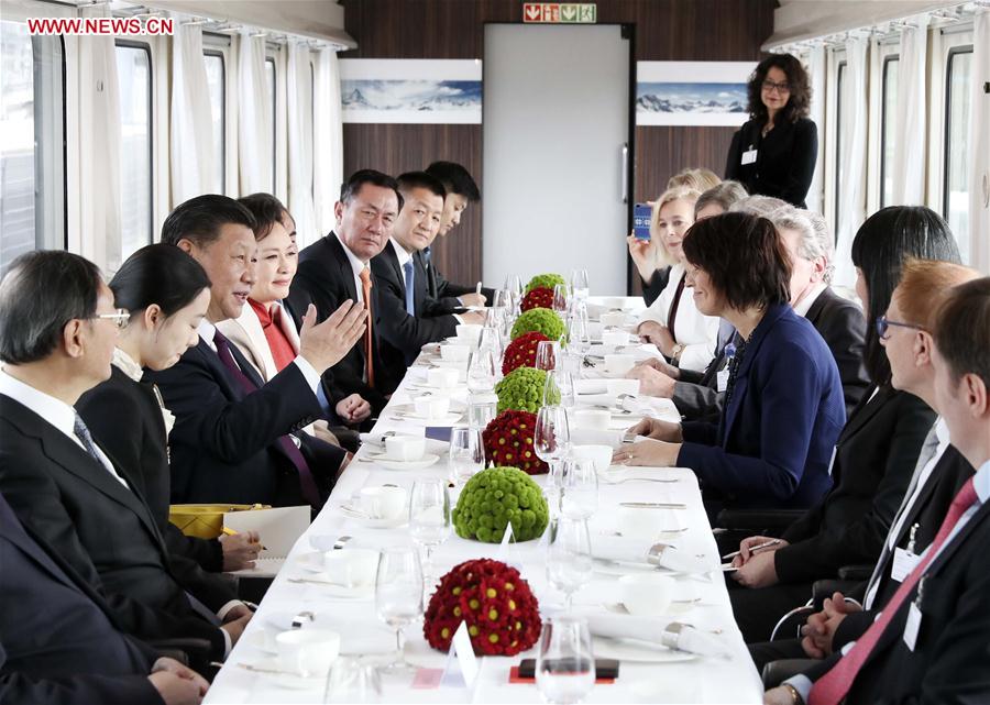 O presidente chinês Xi Jinping e a sua esposa, Peng Liyuan, desfrutam de um chá, enquanto dialogam com a presidente suí?a Doris Leuthard e o seu marido, Roland Hausin, num trem especial do governo, que liga Zurique a Berna, capital da Suí?a.