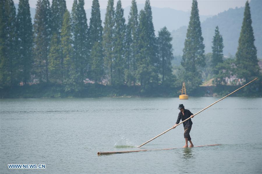 Cidad?o de Hangzhou atravessa rio Xin'an com duas canas de bambu