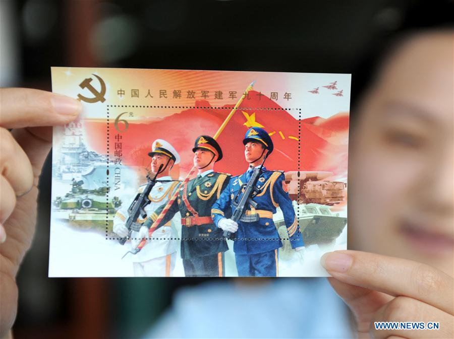 Uma funcionária mostra um selo comemorativo do 90o aniversário do ELP na cidade de Huainan, província de Anhui, no leste da China, a 31 de julho.
