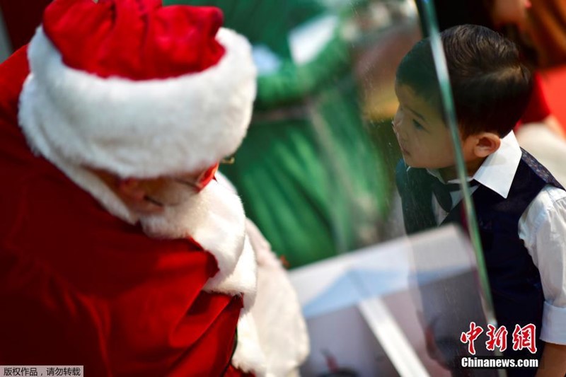 Papai Noel interage com crian?as por vidro durante pandemia